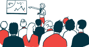 A speaker points to a presentation in front of an audience.