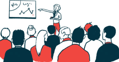 A speaker points to a presentation in front of an audience.